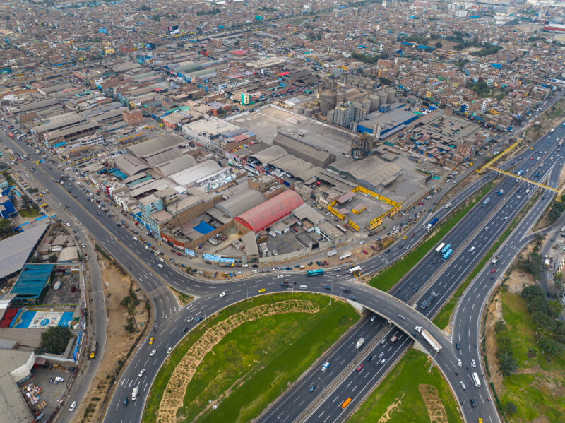 Vista aérea de zona industrial y corredor logístico en Lima Norte, con almacenes, fábricas y autopistas interconectadas que evidencian alta densidad urbana y dinamismo del transporte de mercancías.