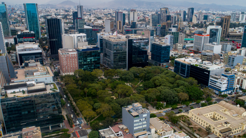 Vista aérea del centro financiero de San Isidro, en Lima, con edificios corporativos y oficinas rodeando una amplia zona verde, reflejando la recuperación del mercado inmobiliario corporativo.